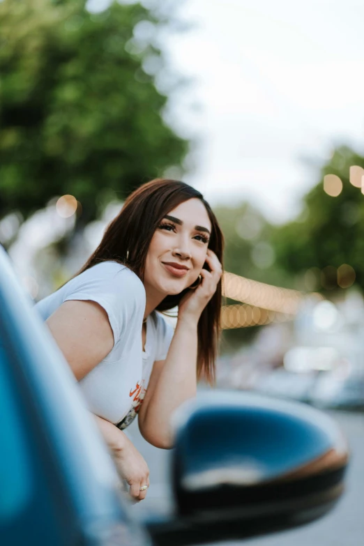 a beautiful young woman leaning on a blue vehicle