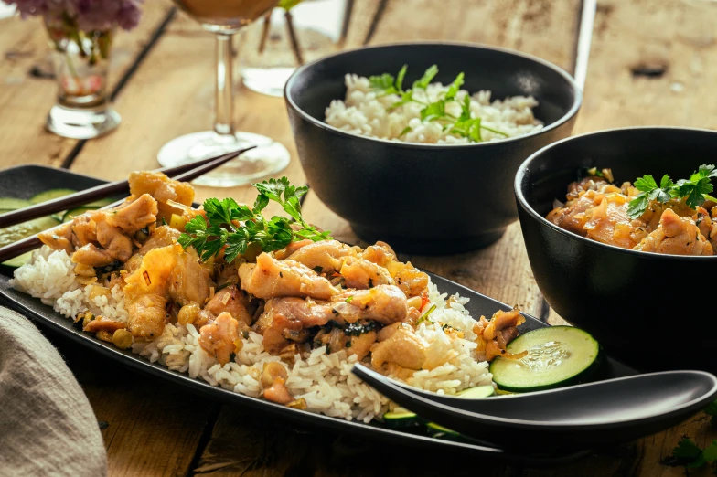 two bowls of food sit on a table, near a plate of rice