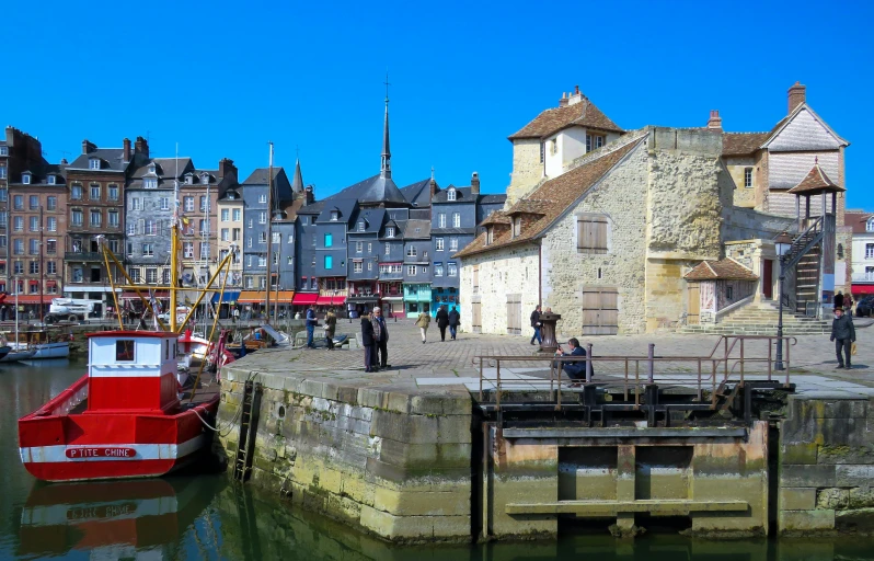 people are standing on a dock in front of old buildings