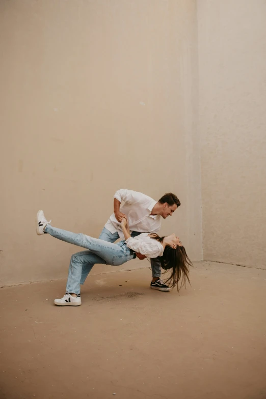 two people standing in a dirty room with one doing a stunt