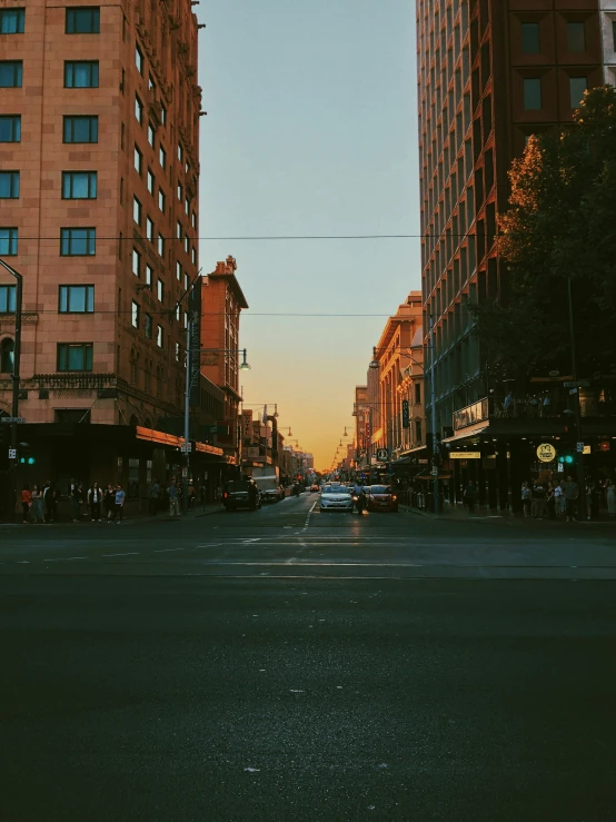 a street with tall buildings is shown at sunset