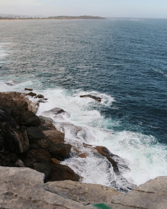 a rock cliff with some white water in the background