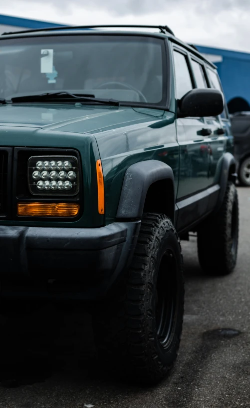 a green jeep with several tires and lights