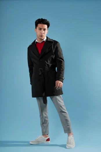 a young man in a black coat posing