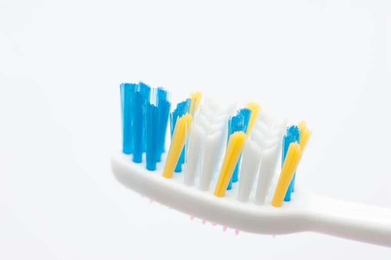 the top half of a toothbrush showing three white and blue bristles