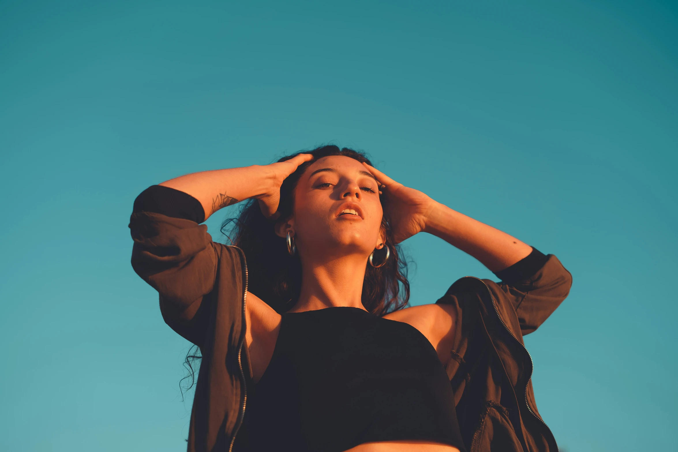 a woman is holding her hair up and looking into the sky