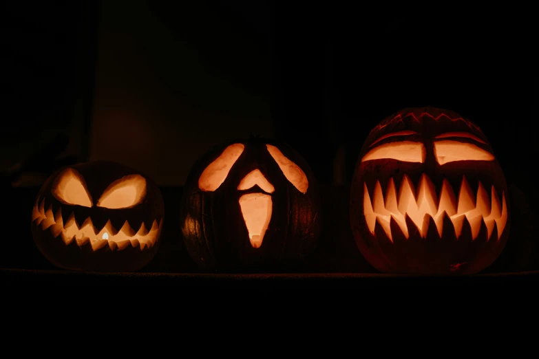 three halloween pumpkin carved to look like faces with mouth teeth