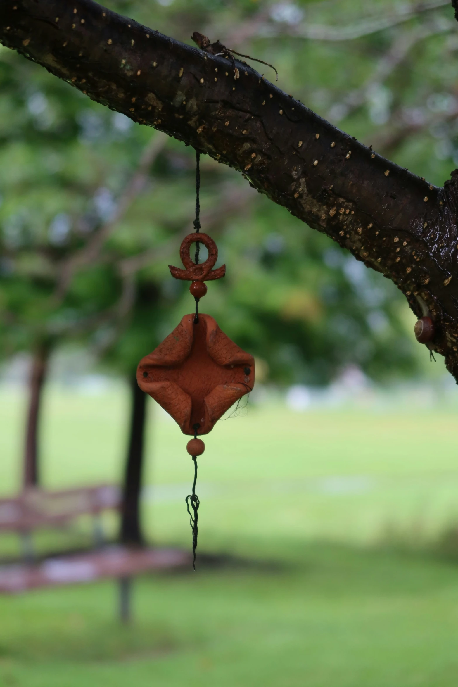 a brown windchime hangs on a tree nch