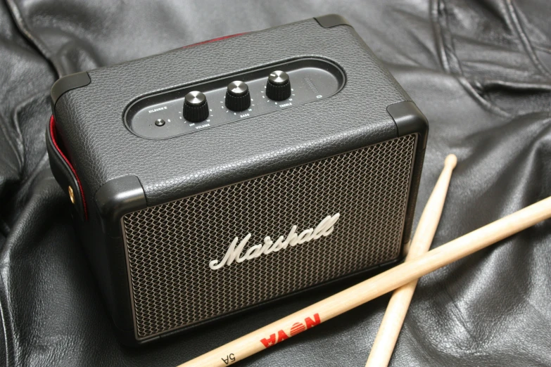 two beaters are beside a black amp with two wooden sticks