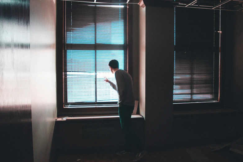 a person standing in front of a window with blinds