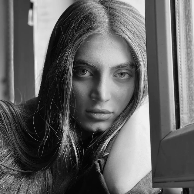 a woman in a sweater sitting next to a wall