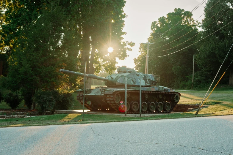 a man sits on the grass in front of a tank that has been parked in front of it