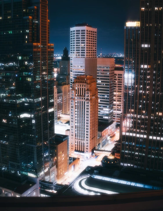 city lights lit up at night with very tall buildings in the foreground