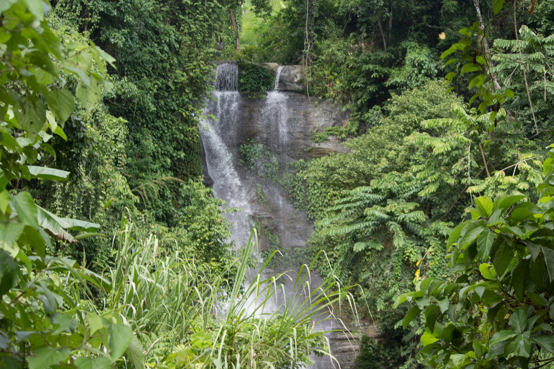 a man riding his motorcycle down a hill near a waterfall