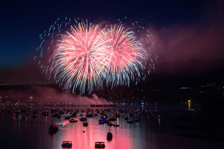 fireworks are in the sky over boats and water