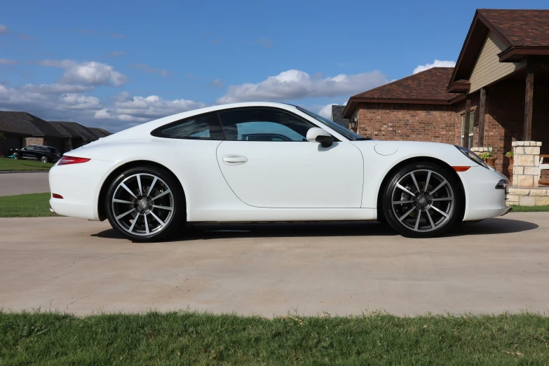 a white sports car sitting in the driveway of a house