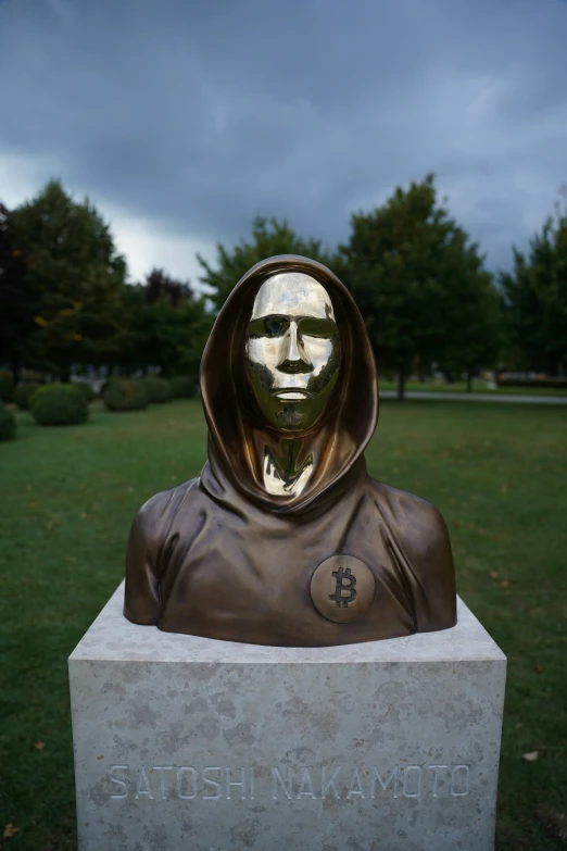 a statue of a person wearing a hood sitting on a white block