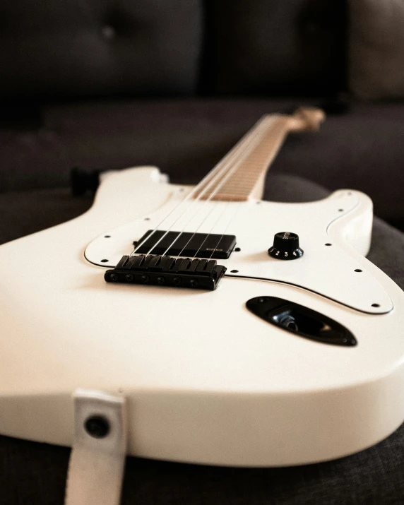 white guitar lying on black velvet surface with backlit