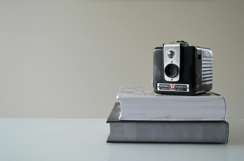 an old po camera sits on top of several books