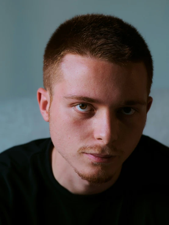 a young man with short hair and beard stares ahead