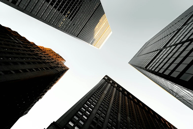 looking up at some tall buildings against a white sky