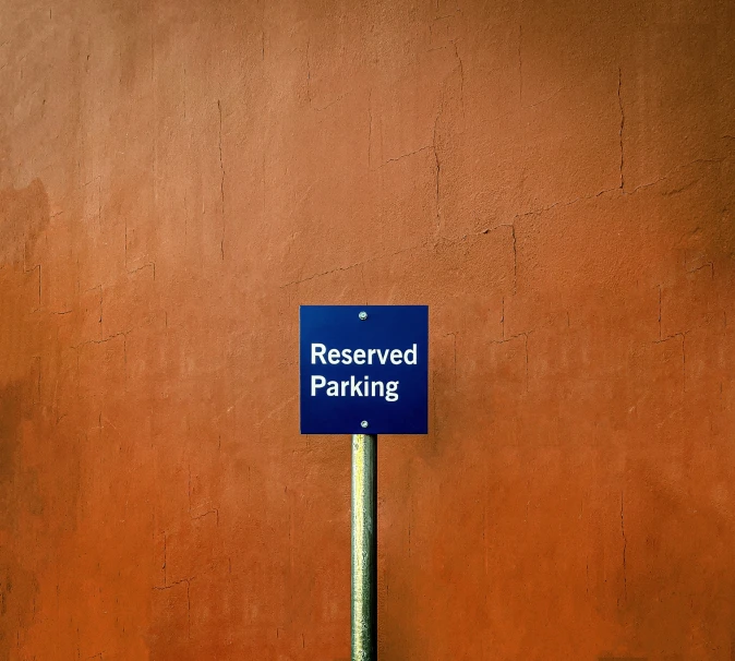 a parking sign sitting next to a brown wall
