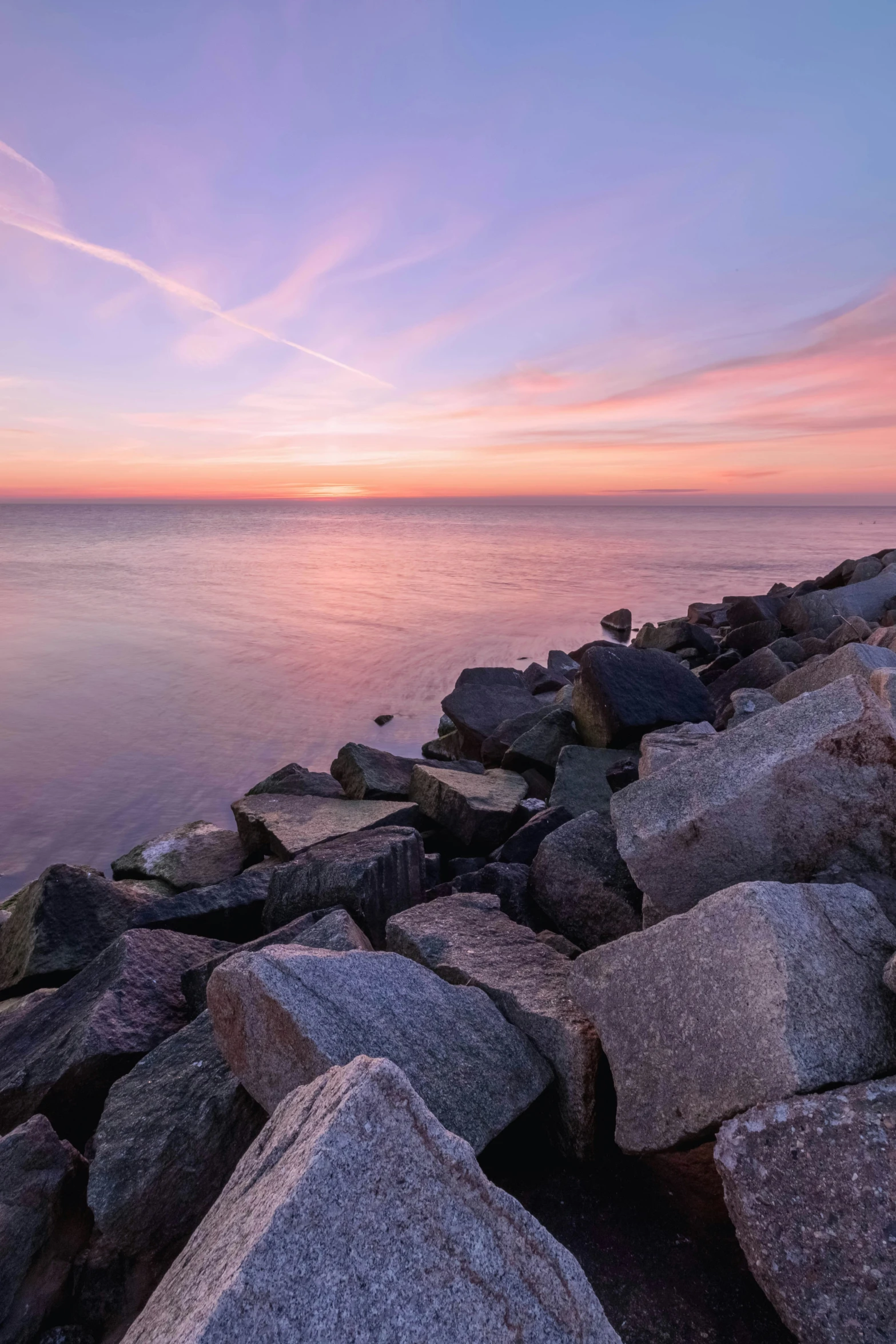 sunset is setting on a calm sea and rocks