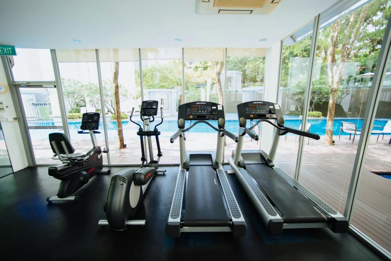 an exercise room with cardio equipment and windows overlooking the pool