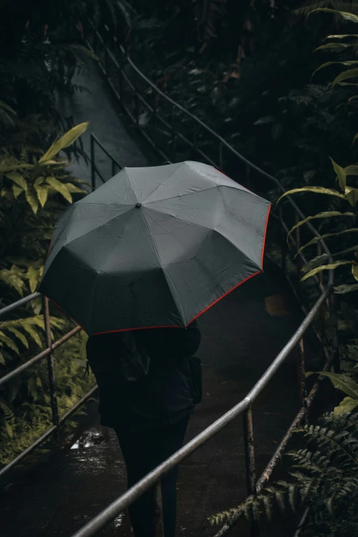 a woman walking across a bridge holding a black umbrella