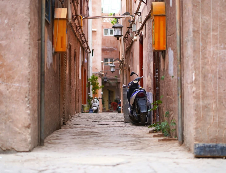 a view of a narrow city street with one motorcycle parked in the alley