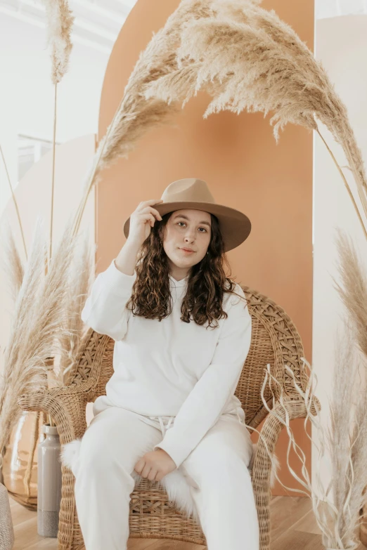 a woman sitting on a wicker chair with feathers