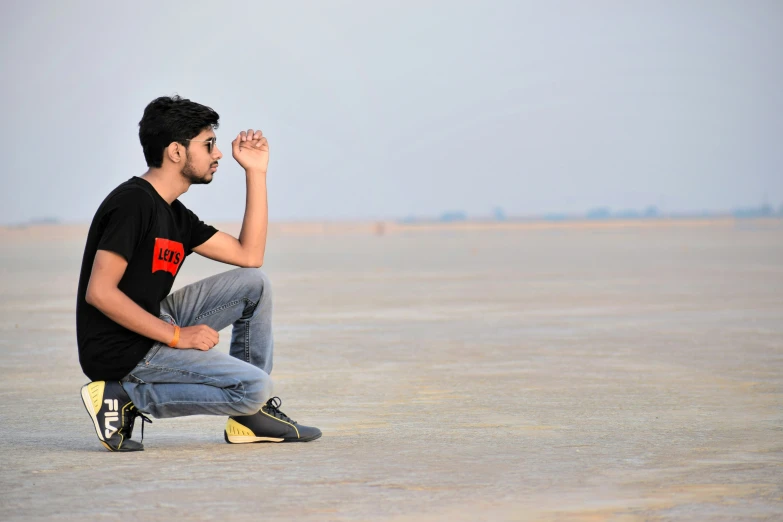 a man kneeling down and pointing up with his fingers