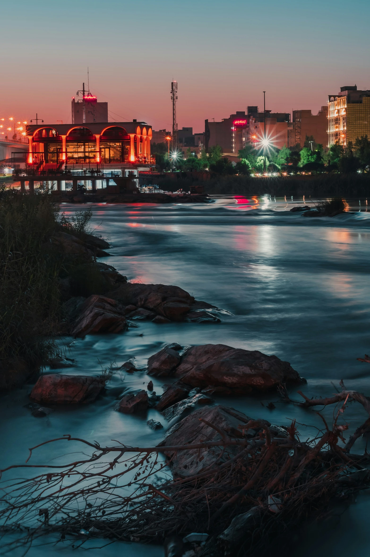 a city at night near a river that is lined with water