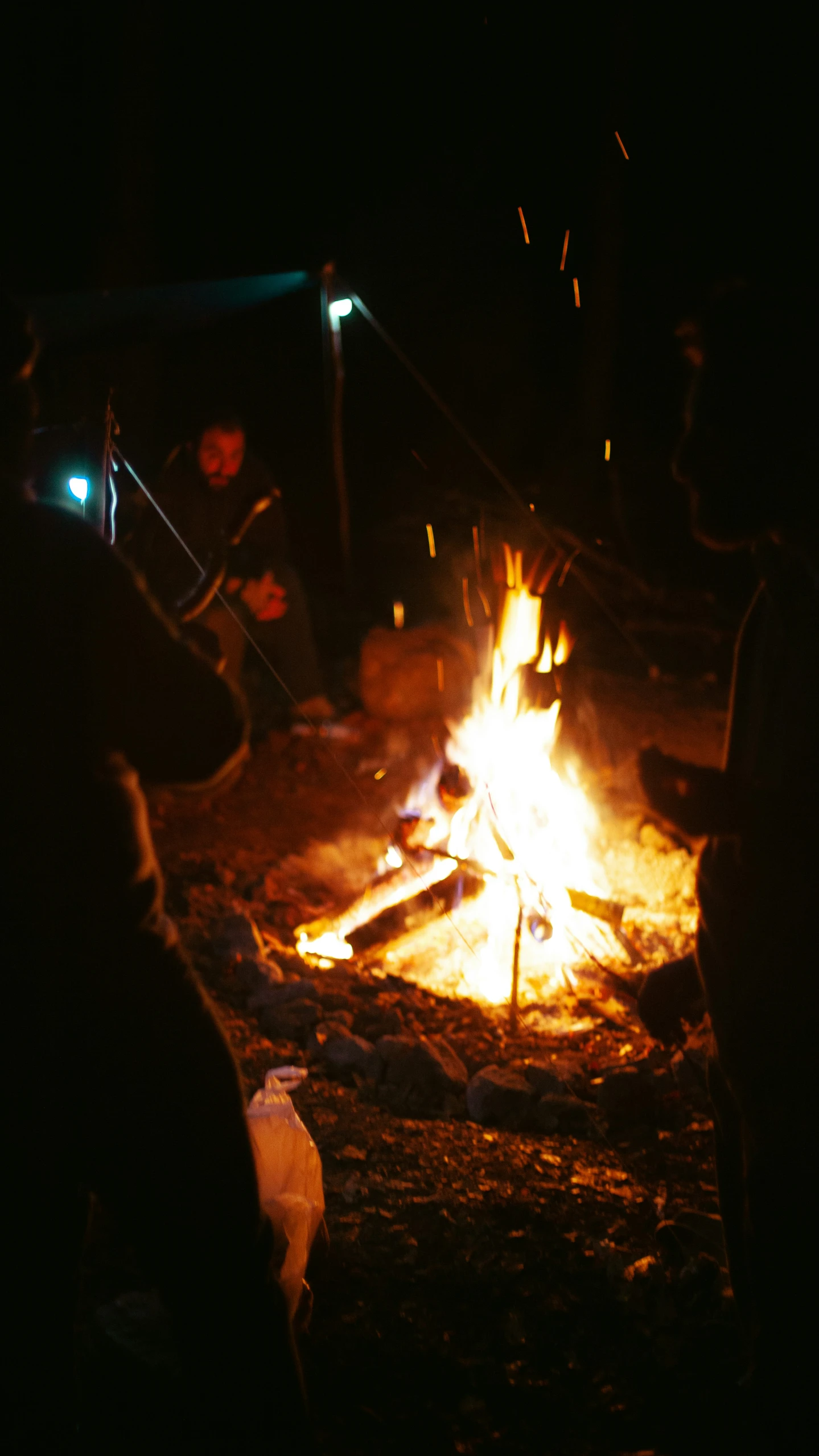 people sitting around a campfire at night in the dark