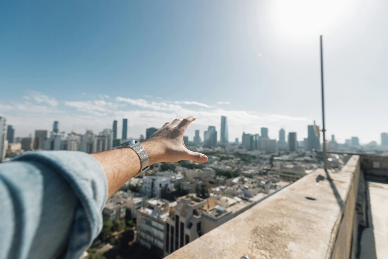 a man holding his hand up to the camera in front of a cityscape