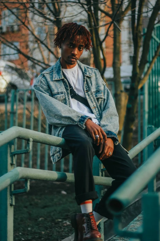 a black man in a jean jacket sitting on some stairs
