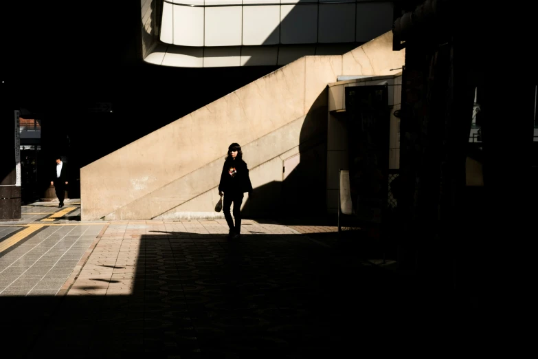 a woman walks down a sidewalk with her hand in her pocket