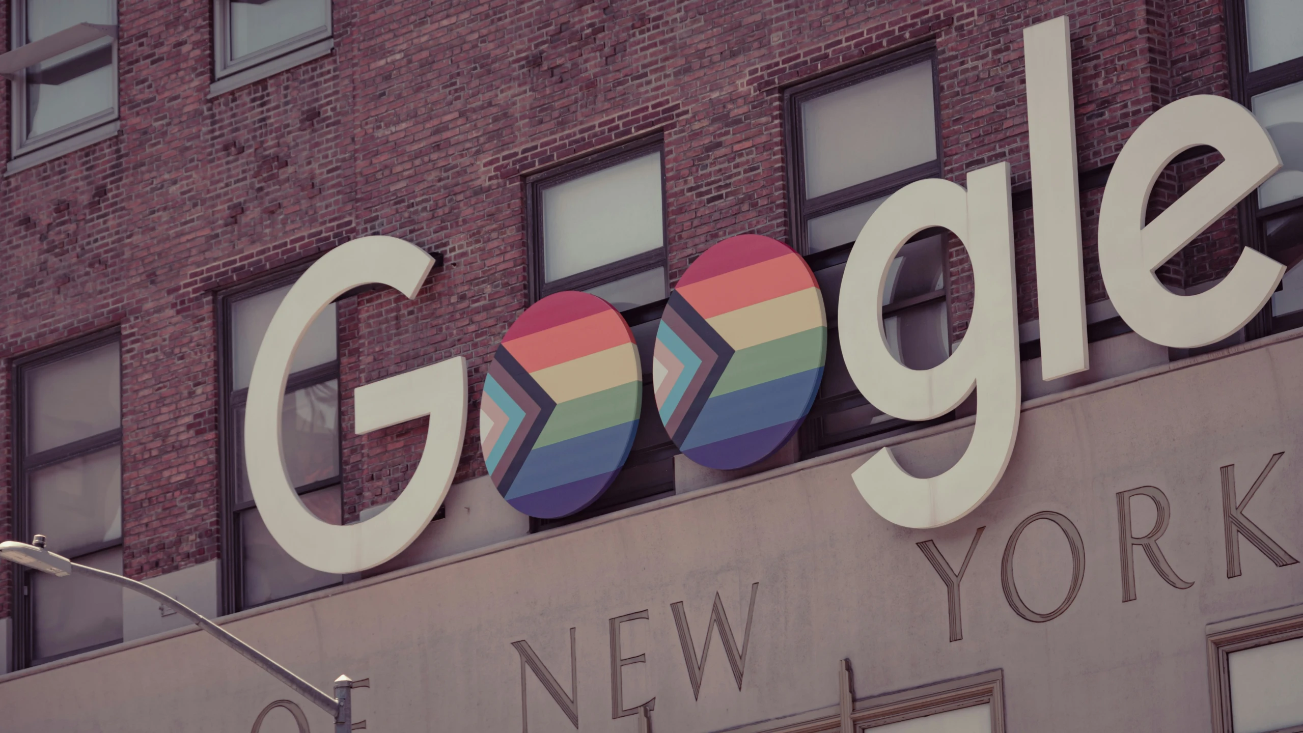 a rainbow colored sign is above the google logo on a building
