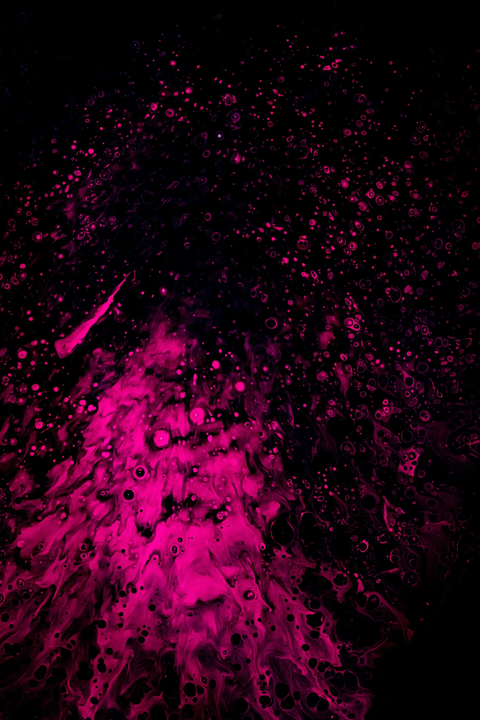 some water bubbles and pink ink on a black background