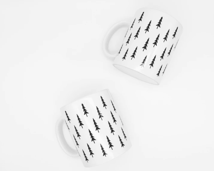 two coffee mugs with christmas trees on them