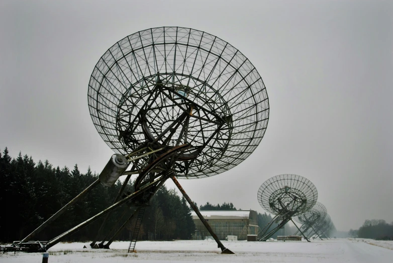 the large array of satellite dish sits on the snowy field