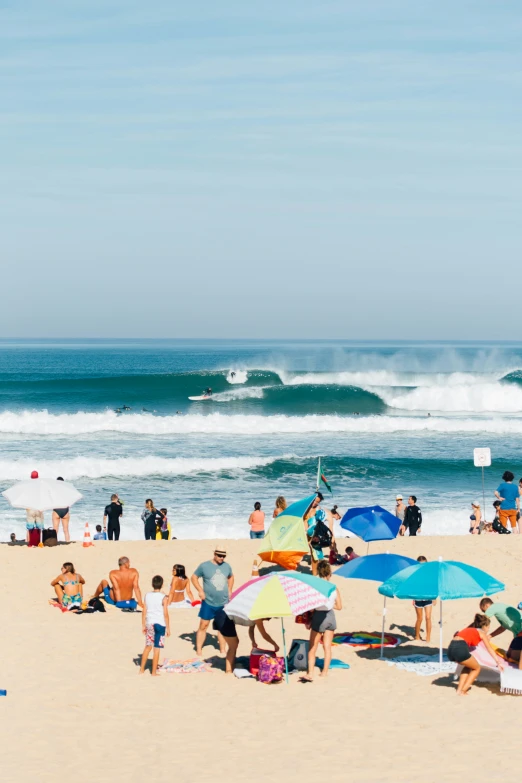 people at the beach with surf boards and umbrellas