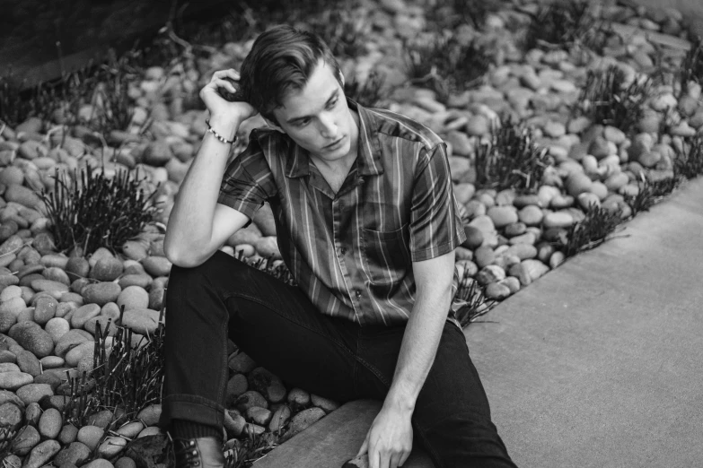 a black and white po of a man sitting on a stone