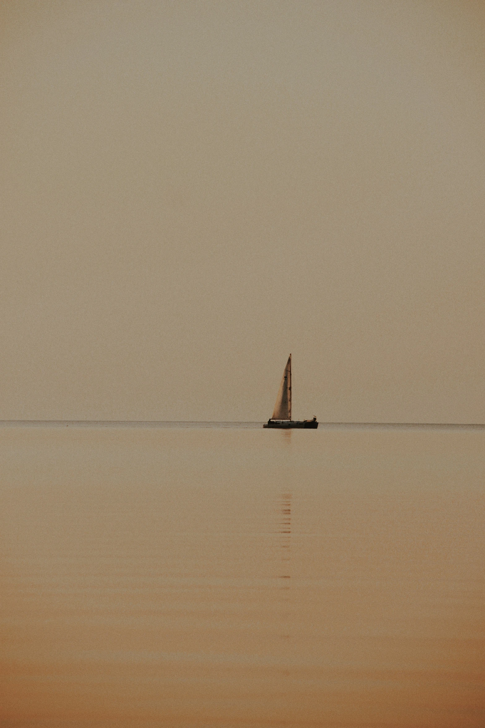 a sailboat with no sails floats on a misty day