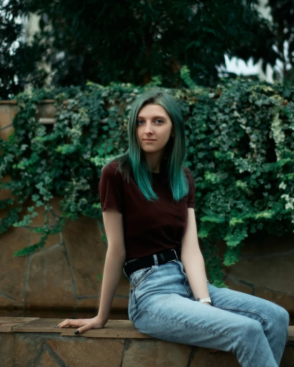 a woman with green hair sitting on a bench next to a tree