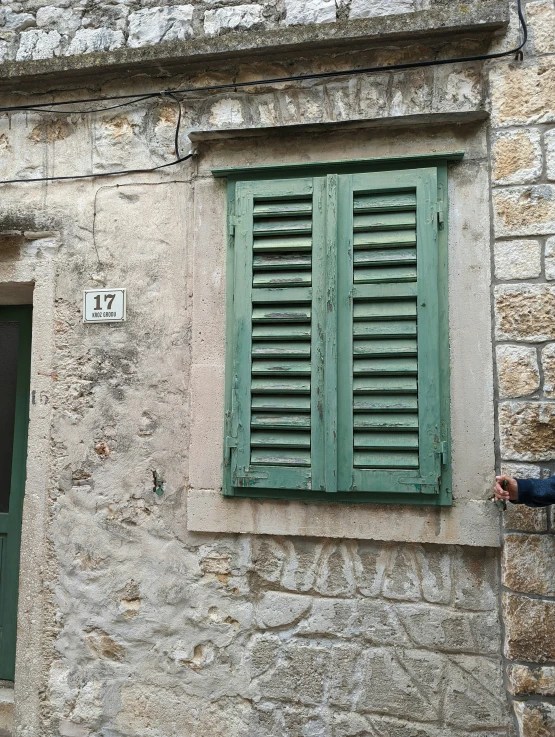 an old building that has green shutters on the windows