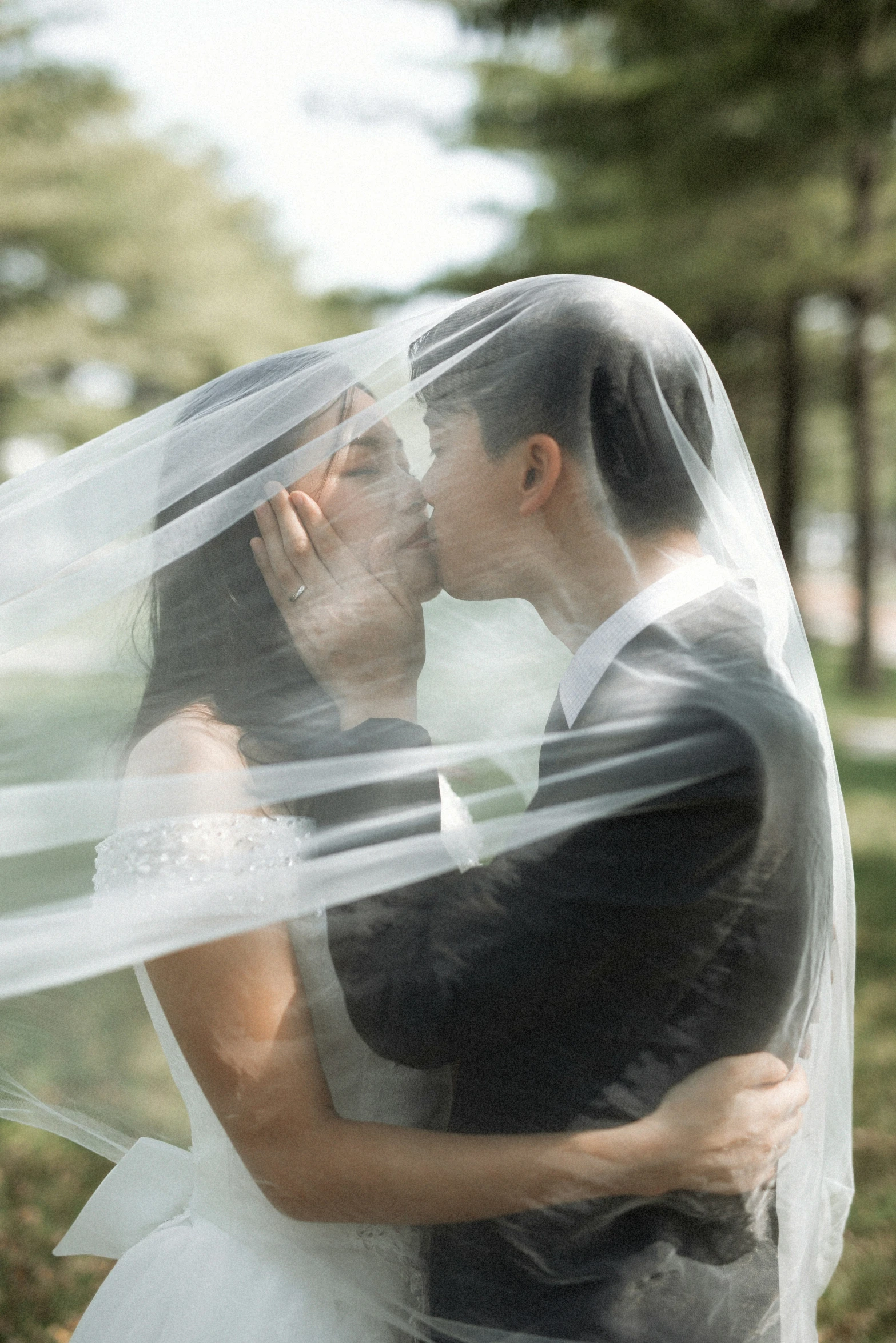 the bride and groom kissing underneath their veil