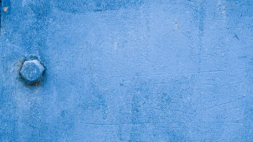 a blue stucco wall with a shoe on the ground