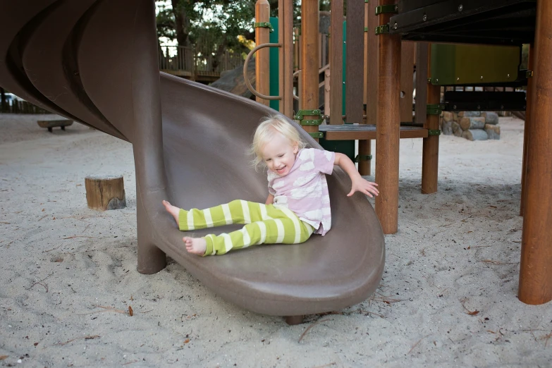 a child sitting on the side of a swing in a playground