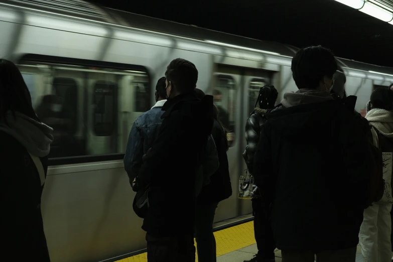 commuters waiting to board a subway train at night